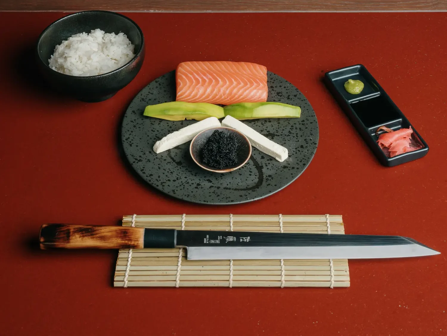Traditional sushi preparation tools including wasabi, ginger, and a bamboo rolling mat